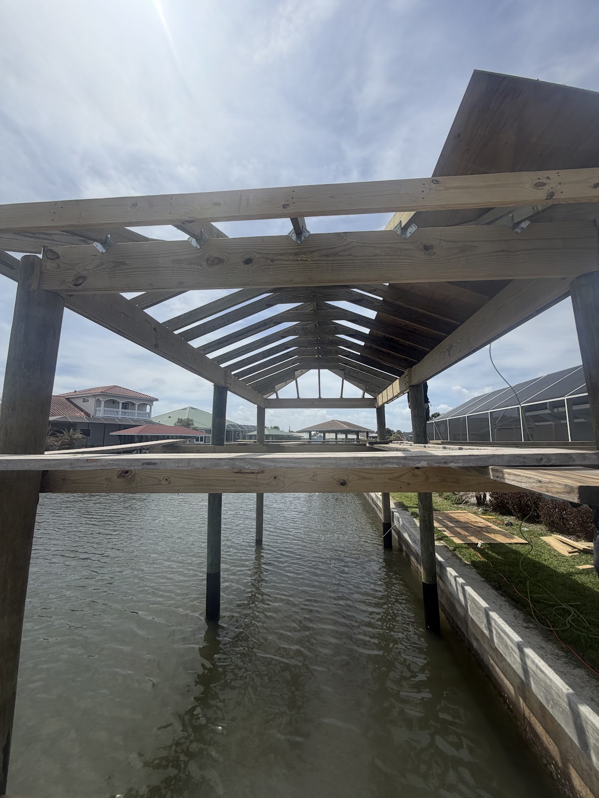 Timber-frame boathouse roof structure under construction over waterway