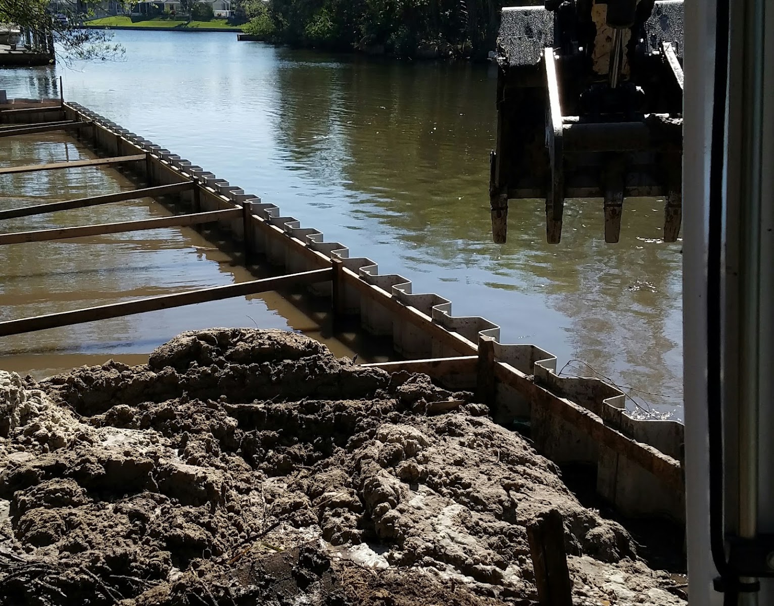 Excavator driving sheet pile panels for major seawall reconstruction